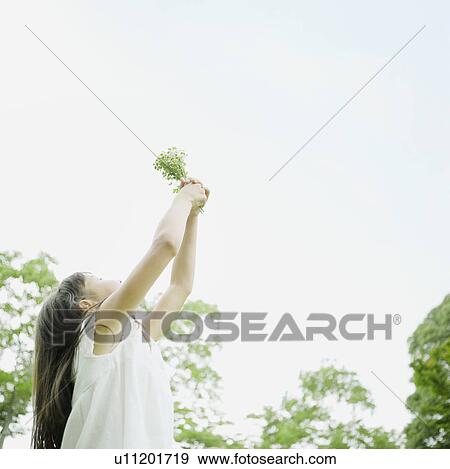 Stock Photo - Girl Holding up Bunch of Wildflowers. Fotosearch