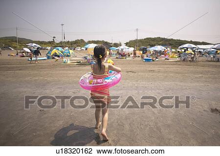 Stock Image - Girl in inner tube at beach. Fotosearch