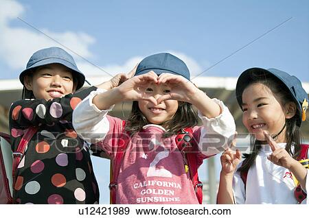 Stock Photo - Girl making heart shape with hands, Japan. Fotosearch