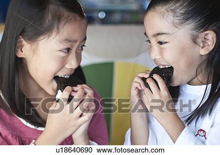 Stock Image - Girls eating rice balls, Japan. Fotosearch