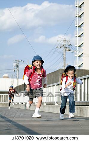 Stock Image - Girls running home from elementary school, Japan. Fotosearch