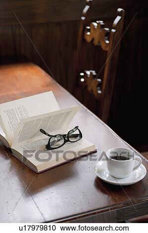 Stock Image - Glasses, Book and Coffee Cup on Wooden Table. Fotosearch