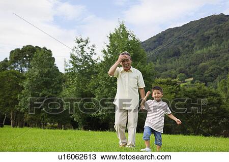 Stock Image - Grandfather and Grandson Walking in Park. Fotosearch