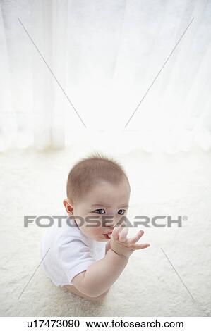 Stock Image - High Angle View of Baby Boy Sucking Thumb. Fotosearch