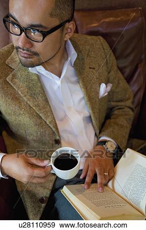 High Angle View of Mature Man Drinking Coffee and Reading Book View Large Photo Image Stock Photo - High Angle View of Mature Man Drinking Coffee and Reading Book. Fotosearch