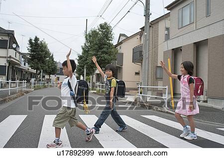Stock Photo - Kids crossing street with hands up, Japan. Fotosearch