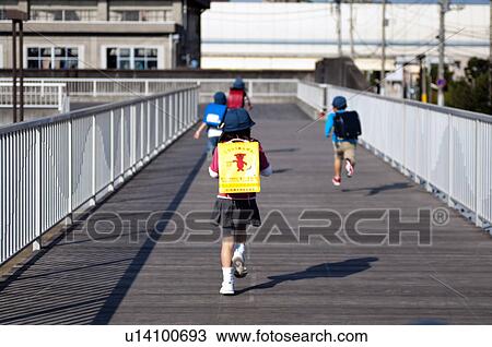 Stock Image - Kids walking and running home, rear view, Japan. Fotosearch