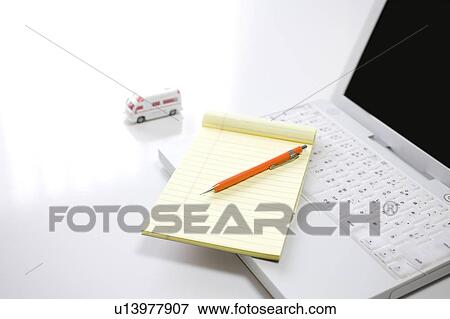 Stock Photo - Laptop, note pad, pen and toy ambulance. Fotosearch