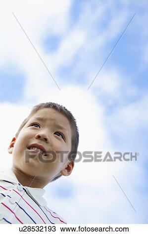 Stock Image - Low Angle View of Boy Against Sky. Fotosearch