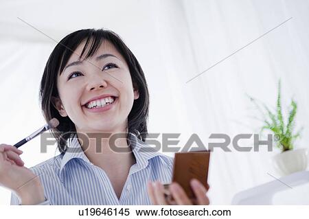 Stock Photography - Low Angle View of Mid Adult Woman Applying Make up. Fotosearch