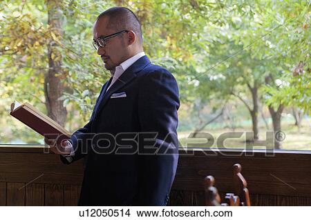 Picture - Mature Man Reading Book on Balcony. Fotosearch