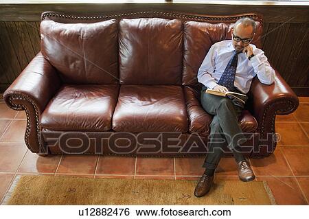 Mature Man Reading Book on Leather Sofa View Large Photo Image Stock Photograph - Mature Man Reading Book on Leather Sofa. Fotosearch