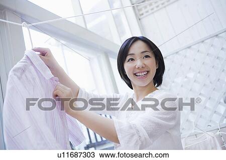 Stock Image - Mid Adult Woman Hanging Clothes to Dry. Fotosearch