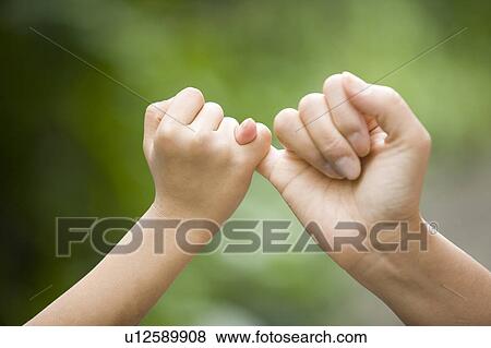 Stock Photo - Mother and child pinky swearing, Japan. Fotosearch