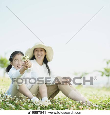 Stock Image - Mother and Daughter Sitting on Grass. Fotosearch