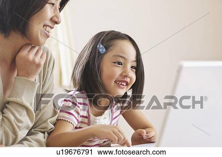Stock Image - Mother and daughter using laptop. Fotosearch