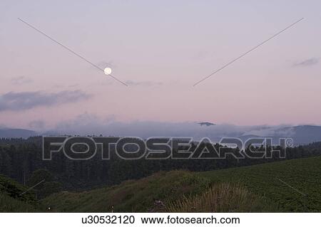 Stock Image - Mountain range and moon, Hokkaido Prefecture, Japan. Fotosearch