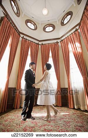 Stock Photo - Newlywed Couple Holding Hands in Old Room. Fotosearch