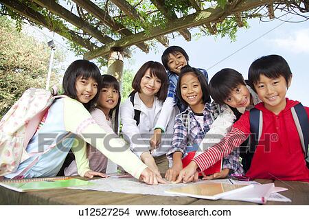 Portrait of school children and female teacher in park, pointing map View Large Photo Image Picture - Portrait of school children and female teacher in park, pointing map. Fotosearch