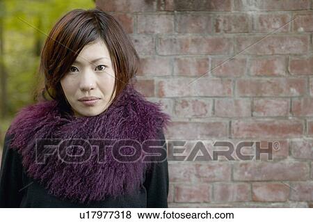 Stock Photo - Portrait of Young Woman Against Brick Wall. Fotosearch