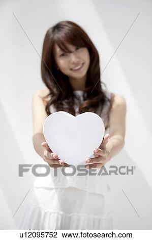 Portrait of young woman holding white heart shaped box, white background, differential focus View Large Photo Image Stock Image - Portrait of young woman holding white heart shaped box, white background, differential focus. Fotosearch