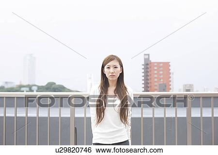 Stock Photograph - Portrait of young woman on rooftop, Japan. Fotosearch