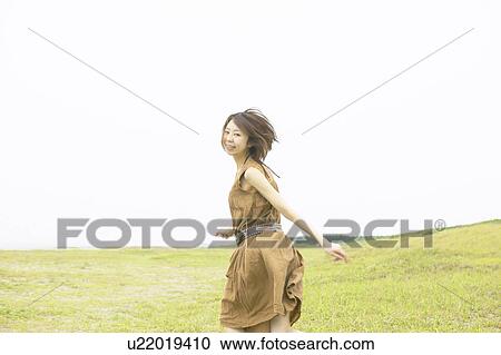 Portrait of young woman running in field, looking back View Large Photo Image Stock Image - Portrait of young woman running in field, looking back. Fotosearch