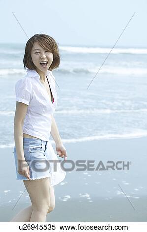 Stock Photography - Portrait of young woman smiling at beach. Fotosearch