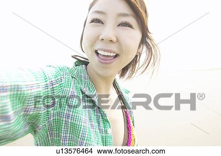 Picture - Portrait of young woman smiling at beach, close up. Fotosearch
