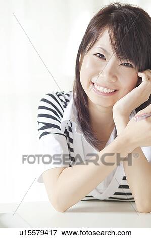 Stock Photo - Portrait of young woman smiling, Japan. Fotosearch