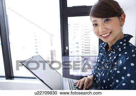 Portrait of young woman using laptop, smiling View Large Photo Image Stock Image - Portrait of young woman using laptop, smiling. Fotosearch