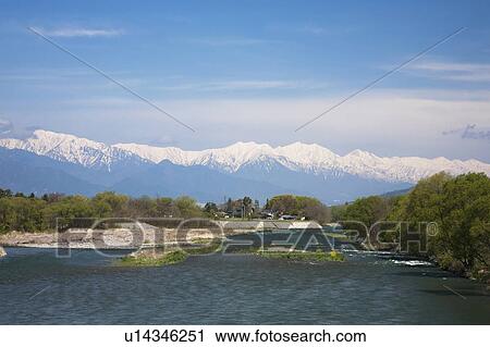 Stock Image - Scenery of River, Snowcapped Mountains in the Background. Fotosearch