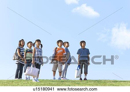 Stock Image - School children standing at riverbank, looking away, copy space. Fotosearch
