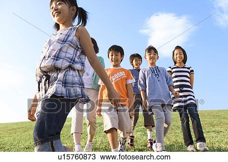 Stock Image - School children with female teacher walking at riverbank, smiling. Fotosearch