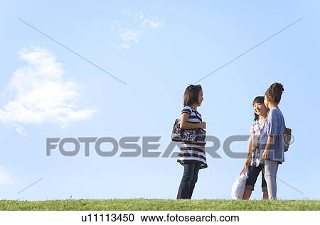 Stock Image - Schoolgirls standing at riverbank, copy space. Fotosearch