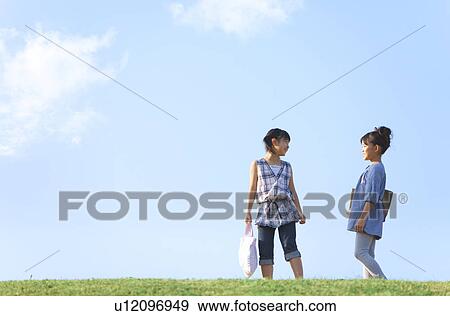 Stock Photo - Schoolgirls standing at riverbank, copy space. Fotosearch