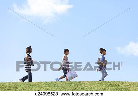 Stock Photo - Schoolgirls walking at riverbank, copy space. Fotosearch