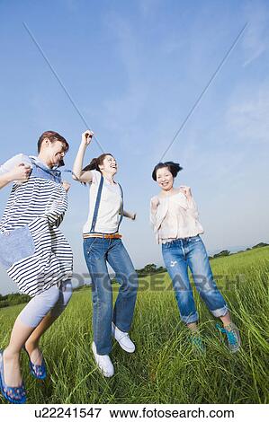Stock Photo - Three Women Jumping in Grass. Fotosearch