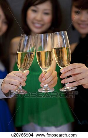 Three young women toasting with glasses of champagne, black background, differential focus View Large Photo Image Picture - Three young women toasting with glasses of champagne, black background, differential focus. Fotosearch