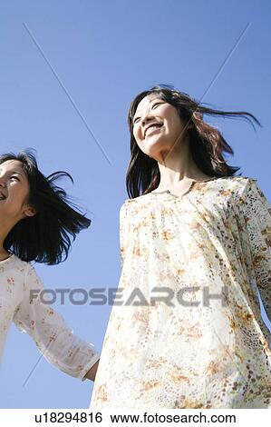 Stock Photograph - Tow Young Women Smiling Under Blue Sky. Fotosearch