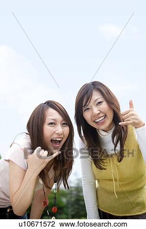 Stock Image - Two happy young women gesturing, copy space. Fotosearch