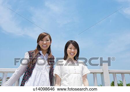 Stock Photograph - Two Young Women Against Blue Sky. Fotosearch