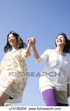 Two Young Women Holding Hands and Jumping View Large Photo Image Picture - Two Young Women Holding Hands and Jumping. Fotosearch