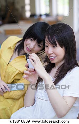 Stock Photo - Two Young Women Looking at Digital Cameras. Fotosearch