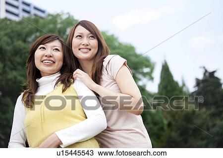 Two young women smiling and looking away View Large Photo Image Stock Image - Two young women smiling and looking away. Fotosearch