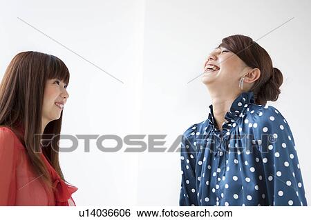 Stock Photograph - Two young women smiling, white background. Fotosearch