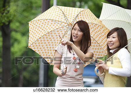Two young women with umbrella, smiling View Large Photo Image Stock Image - Two young women with umbrella, smiling. Fotosearch