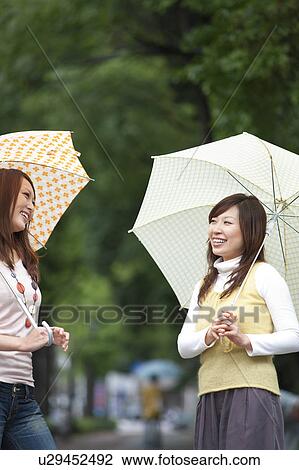 Two young women with umbrella, smiling View Large Photo Image Stock Image - Two young women with umbrella, smiling. Fotosearch