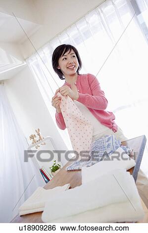 Stock Photograph - Woman Folding Clean Clothes. Fotosearch