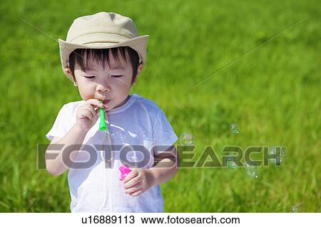 Stock Image - Young Boy Blowing Soap Bubbles. Fotosearch